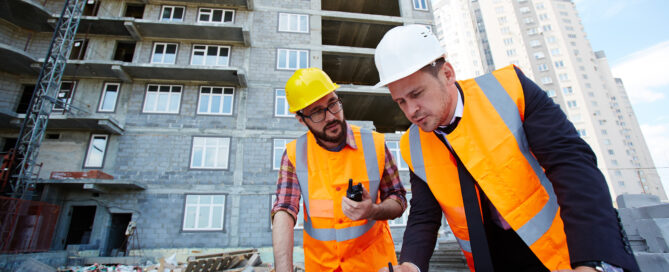 Construction managers reviewing blueprints at a building site. 